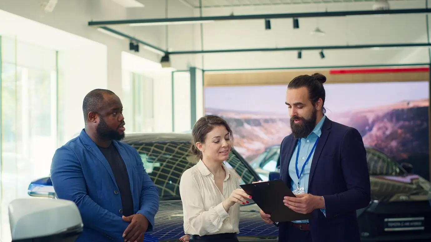 Autohausverkäufer, der Kunden Fragen stellt.