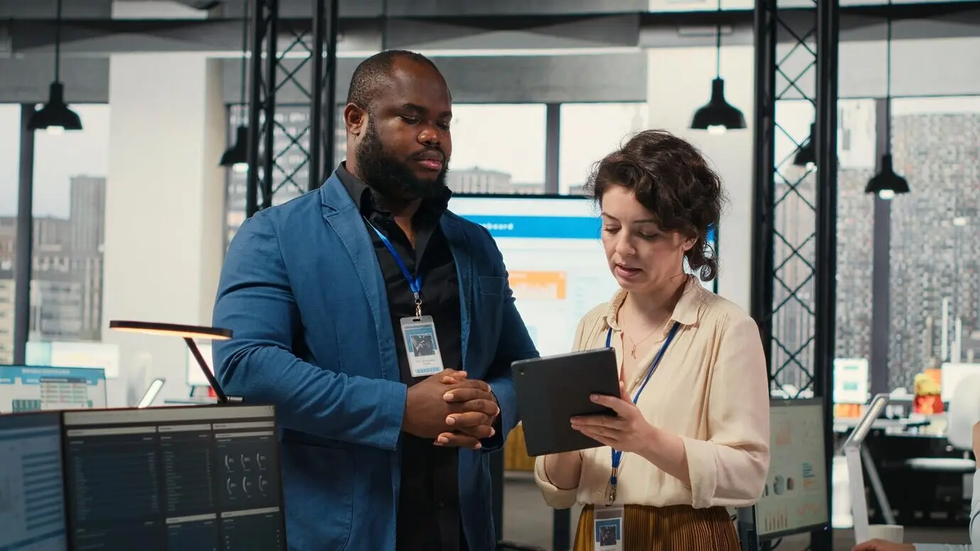 Zwei Mitarbeitende prüfen Datenerkenntnisse auf einem Tablet in einer professionellen Arbeitsumgebung und entwickeln das Geschäft.